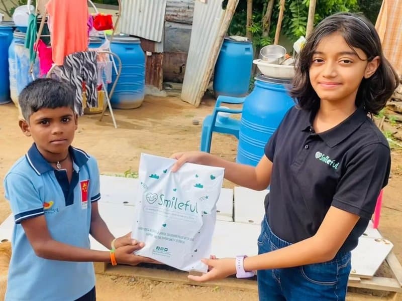A young volunteer presenting a Smileful package to a child